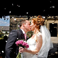 A newly wedded couple kiss in front of the church